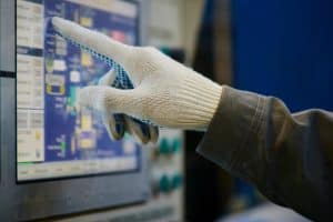 Die Hand des Arbeiters klickt auf das Touchscreen-Bedienfeld.